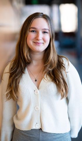 Margaux Petruska poses for a photo leaning against at wall and smiling at the camera.